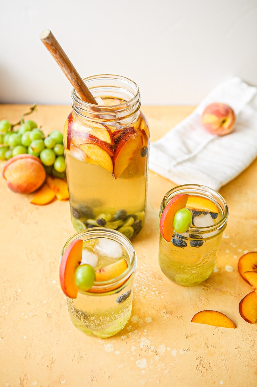 White wine and elderflower sangria in a large mason jar and two glasses