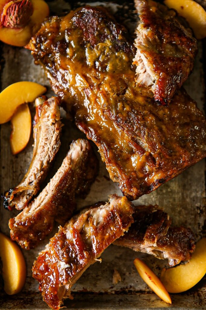 A full rack of ribs on a platter with a few single ribs