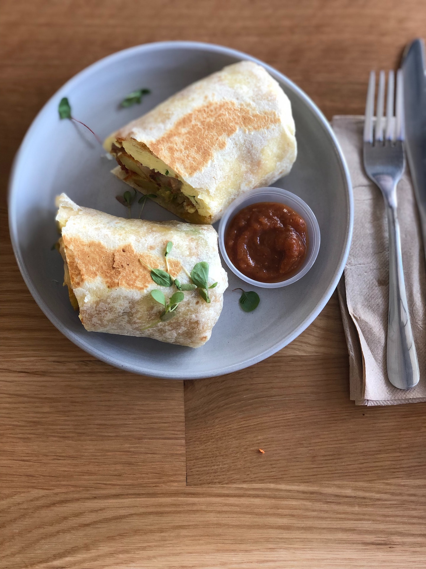 a breakfast burrito sitting on a plate with salsa on the side